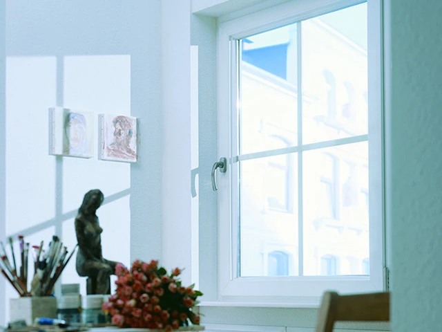 Helles Atelier mit WIRUS Fenster, Pinsel, Skulptur und Blumenstrauß am Tisch