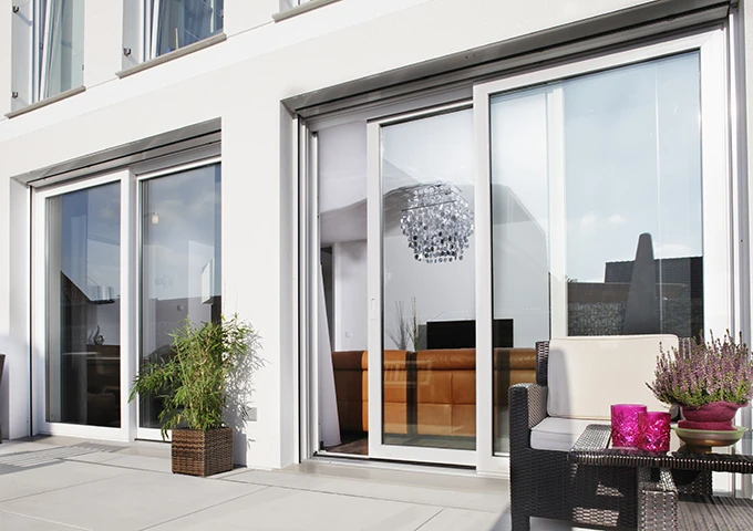 Moderne Terrasse mit Schiebetür, Lounge-Möbeln und Pflanzen vor Haus