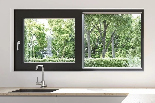Modernes WIRUS Schiebefenster in der Küche mit dunklem Rahmen über der Spüle; große Glasflächen bieten viel Tageslicht und freien Blick ins Grüne.